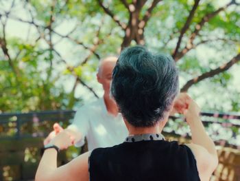 Rear view of man holding ice cream against trees