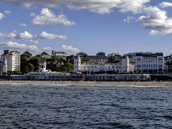 Sea by buildings against sky in city