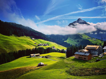 Scenic view of green landscape and mountains against sky