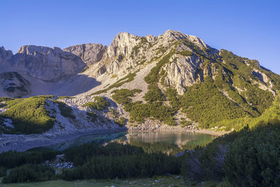 Scenic view of lake and mountains against clear blue sky