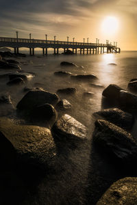 Pier on sea at sunset
