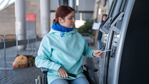 Woman in a wheelchair does not reach the self-service checkout at the railway station. 