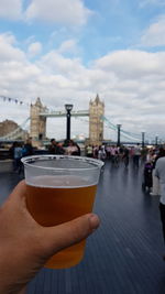 Midsection of man holding a beer against sky in city