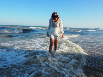 Woman standing at shore against clear sky