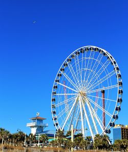 Low angle view of ferris wheel against clear blue sky