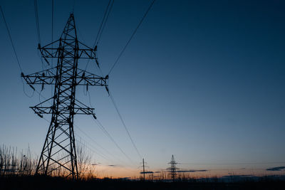 Low angle view of silhouette electricity pylon against clear sky