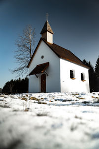 Snowy land and church against clear blue sky