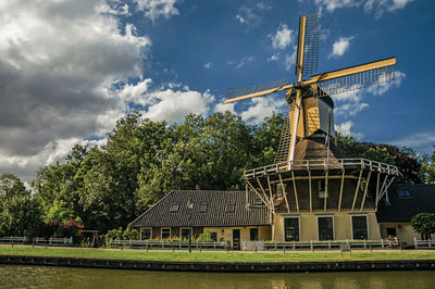 Traditional windmill by trees against sky