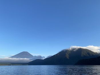 Scenic view of sea and mountains against blue sky