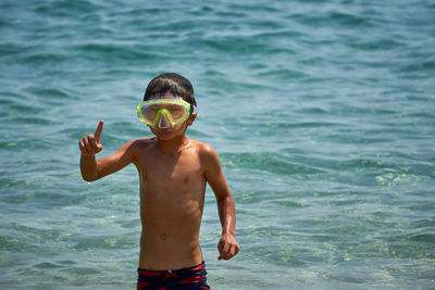 Shirtless boy gesturing while snorkeling in sea