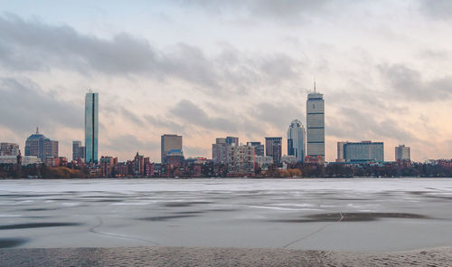 City at waterfront against cloudy sky