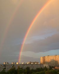 Rainbow over city against sky