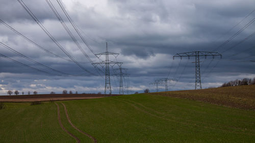 Electricity pylon on field against sky