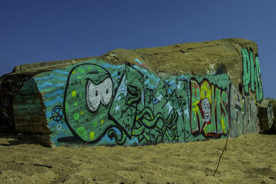 Graffiti on beach against clear sky