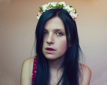 Portrait of woman wearing flowers against wall