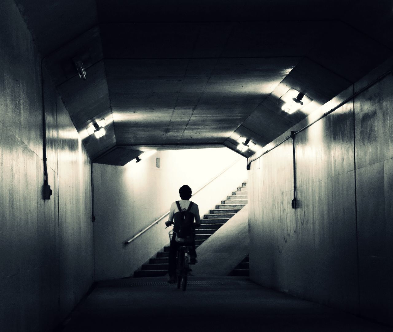 REAR VIEW OF MAN WALKING IN SUBWAY TUNNEL