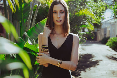 Portrait of young woman standing against plants