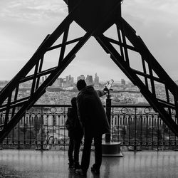 Rear view of man with son by coin-operated binoculars at eiffel tower