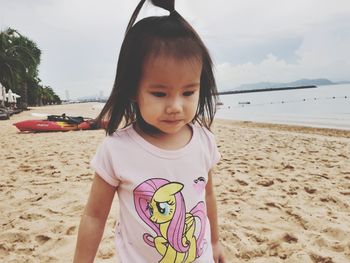 Cute girl standing at beach against sky