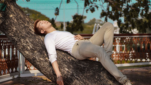 Young man lying on tree trunk