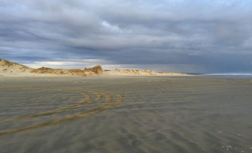 Scenic view of beach against cloudy sky