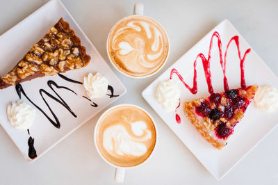 Directly above of pastry with cappuccinos served on table