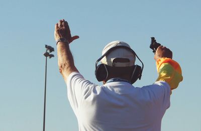 Low angle view of man holding umbrella against clear sky