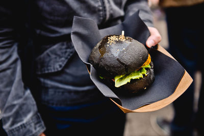 Midsection of person holding hamburger at market