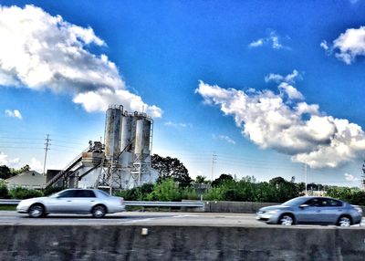 Cars on road against cloudy sky