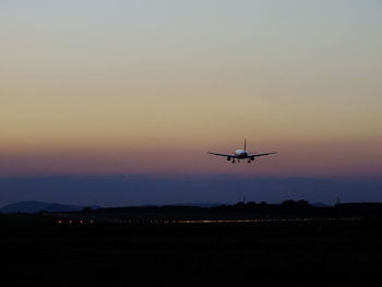 Airplane flying in sky at sunset