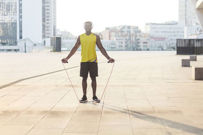 Rear view of man walking on footpath against buildings in city