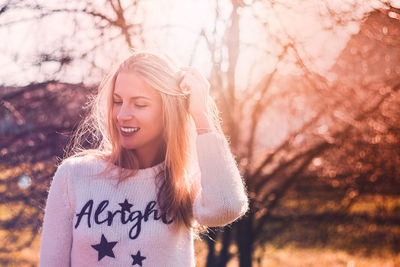 Portrait of smiling young woman against tree