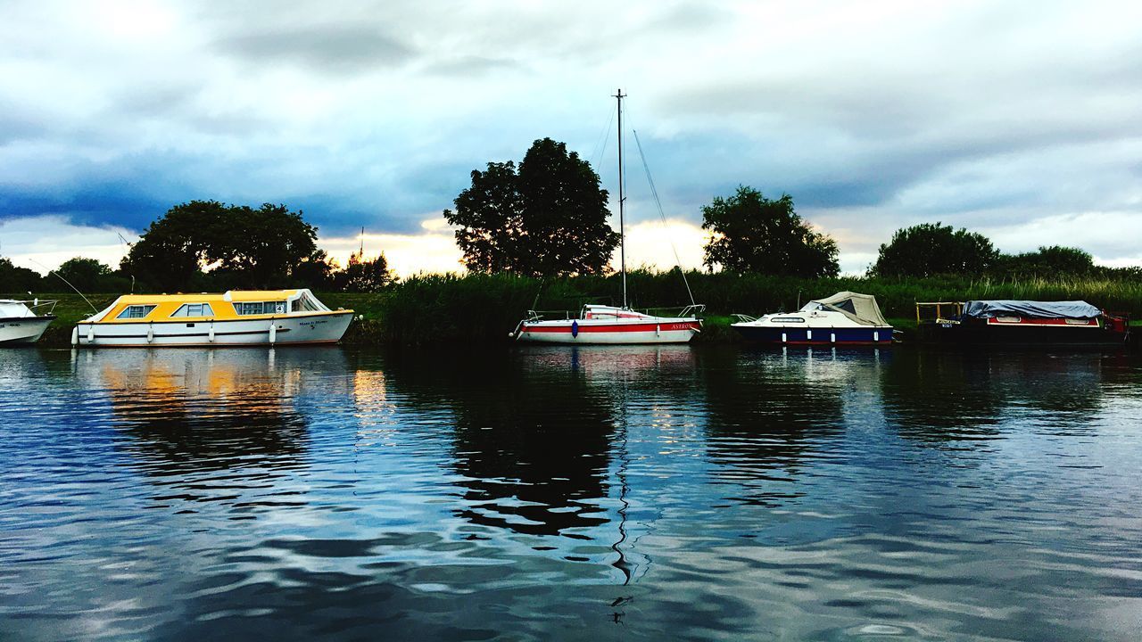 BOATS MOORED ON WATER AGAINST SKY