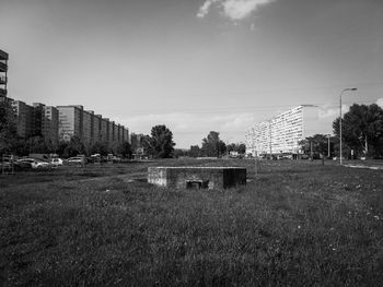 Field by buildings against sky