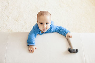 Portrait of cute baby lying on sofa at home