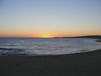 Scenic view of beach against clear sky during sunset