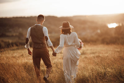 Rear view of couple walking on field