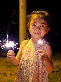 Young woman blowing sparkler at night