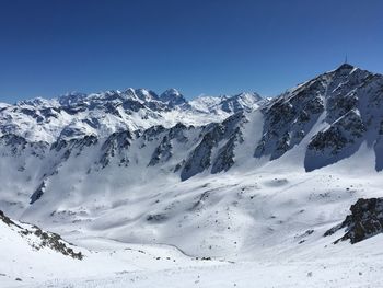 Scenic view of snowcapped mountains against blue sky