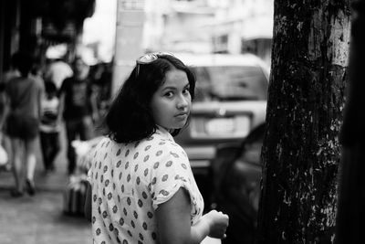 Portrait of young woman standing on footpath