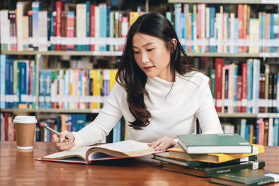 Young woman sitting on book at table