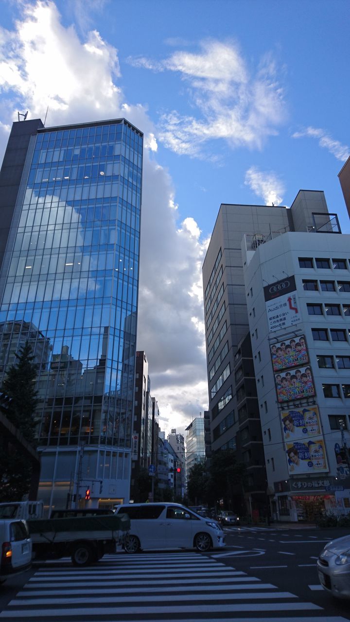 building exterior, architecture, built structure, city, land vehicle, sky, mode of transport, road, office building, skyscraper, modern, building, cloud - sky, city life, tall - high, city street, cloud, day, outdoors, blue, the way forward, no people, travel destinations, cloudy, tall