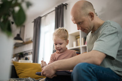 Side view of man using mobile phone while sitting at home