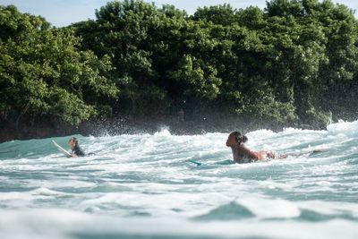 Man swimming in sea against trees