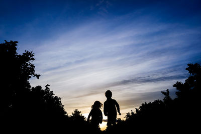 Silhouette kids against sky during sunset