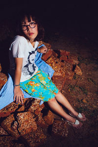 Young woman looking away while sitting on land