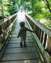 Rear view of girl walking on footbridge