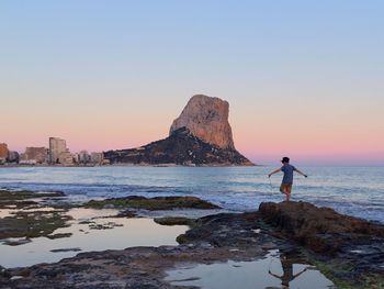 Rear view of a boy overlooking calm sea