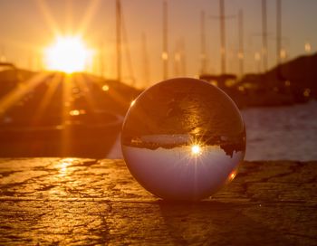 Close-up of crystal ball against sun during sunset 