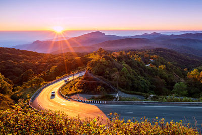 High angle view of light trails on road by mountains against sky